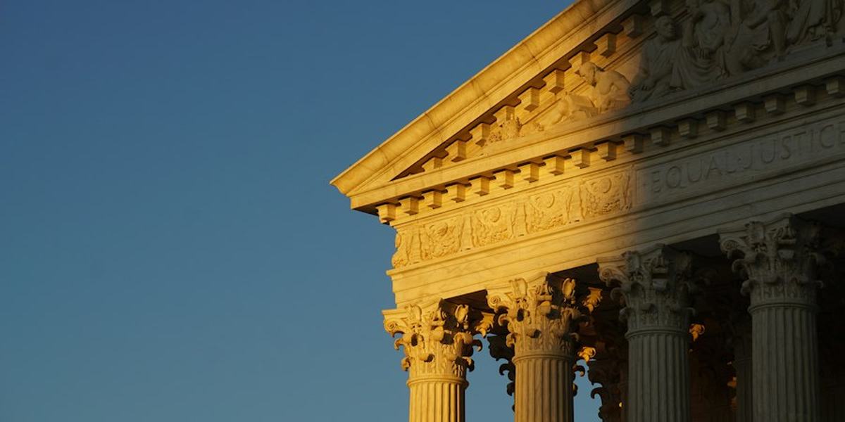The columns and pediment of a courthouse in warm light